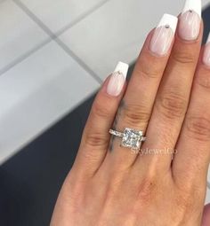 a woman's hand with white nails and an engagement ring