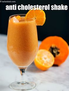 an orange drink in a glass next to sliced oranges on a table with text overlay that reads anti cholesterol shake