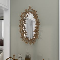 a mirror hanging on the wall above a table with a vase and glass bottle next to it