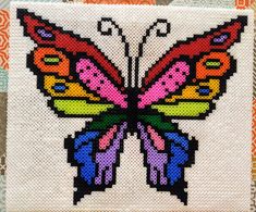 a cross - stitch butterfly is shown on an orange and white background