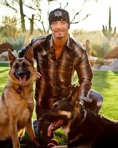 a man kneeling down next to two dogs