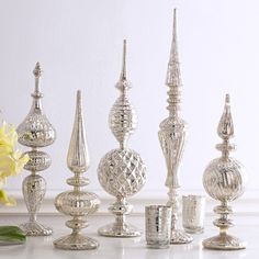 a group of silver candlesticks sitting on top of a table next to a yellow flower