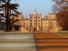 an old building with trees in front of it and the sun shining on the ground