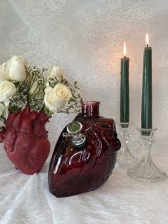 two vases with flowers and candles on a white table cloth next to each other