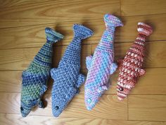 three knitted fish sitting on top of a wooden floor