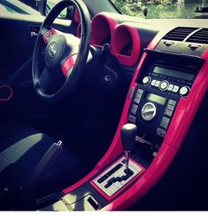 the interior of a car with pink trim and steering wheel, dash board, and dashboard controls