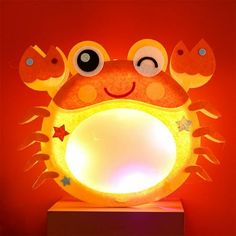 a light up crab sitting on top of a wooden table next to a red wall