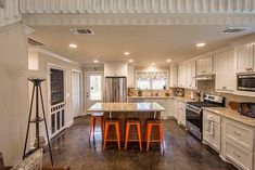 a kitchen with white cabinets and an island in the middle of the room, along with three stools