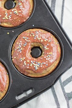 three donuts in a muffin pan with sprinkles