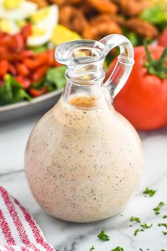 a glass bottle filled with dressing next to a salad