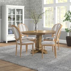 a dining table with four chairs and a potted plant in the middle of it