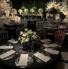 the table is set for an event with white flowers and greenery in centerpieces