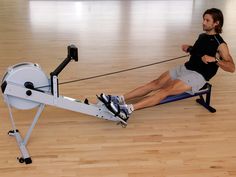 a man sitting on a rowing machine in an empty room with hard wood flooring