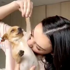 a woman holding a small dog up to her face