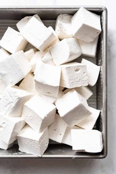 marshmallows in a metal container on a white surface