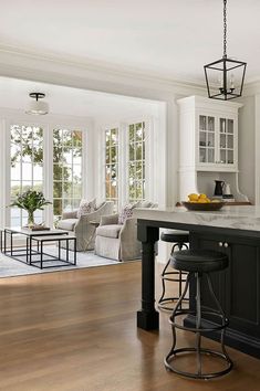 a kitchen island with stools in front of an open living room and dining area