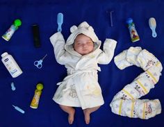 a baby laying on top of a blue blanket next to toothbrushes and other items