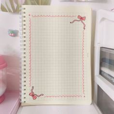 an open notebook with pink bows on it sitting on a counter next to a microwave