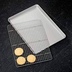 three cookies on a cooling rack next to a baking sheet