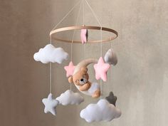 a teddy bear is sitting on a cloud mobile with pink and grey stars hanging from it