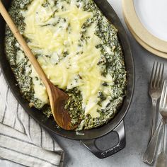 spinach and cheese casserole in a skillet with a wooden spoon