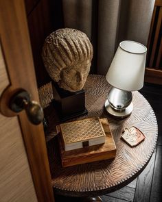 a table with a lamp, books and a vase on it next to a door