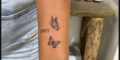 a woman's arm with three butterflies on it and the word boo written in black ink