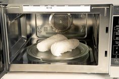 two uncooked fish are sitting in an open microwave oven with the door ajar