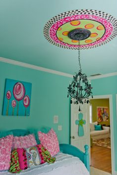 a chandelier hangs from the ceiling above a bed in a room with blue walls