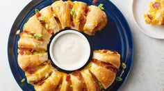 a blue plate topped with sandwiches next to a cup of ranch dressing on top of it