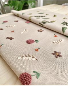 two pieces of fabric with flowers and leaves on them sitting on top of a table