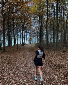 a woman walking down a leaf covered road