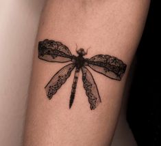 a black dragonfly tattoo on the arm