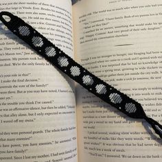 an open book with a black and white crochet bracelet on top of it