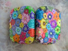 two colorful flower covered rocks sitting on top of a white tableclothed surface with flowers painted on them