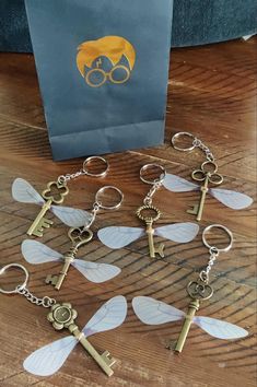 six key chains with various keys attached to them on a wooden table next to a bag