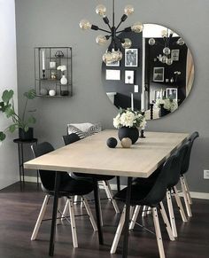 a dining room table with black chairs and a round mirror on the wall