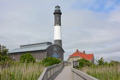 a light house sitting on top of a lush green field next to tall grass and trees