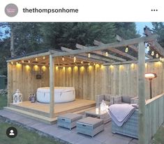 an outdoor hot tub and patio with lights on the roof, surrounded by wood planks