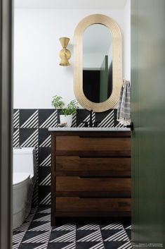 a bathroom with black and white checkered flooring, a gold framed mirror above the sink