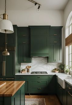 a kitchen with dark green cabinets and white counter tops, an island in the middle