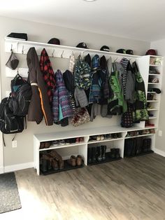 a coat rack filled with lots of coats and shoes next to a wall mounted shelf