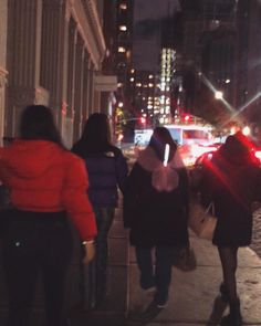 several people walking down the sidewalk at night