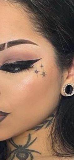 a woman with black and white makeup has spider tattoos on her upper half of her face