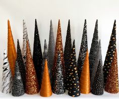 there are many black and orange trees on the shelf together, each with different designs