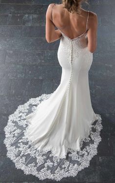 a woman in a white wedding dress is looking down at her back, with an intricate lace