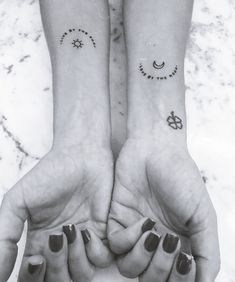 two people holding hands with tattoos on their wrists and fingers, both showing the same symbol