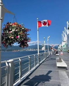 the canadian flag is flying high over the water and on the side of a pier