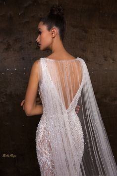 the back of a woman wearing a white wedding dress with sheer, beaded detailing