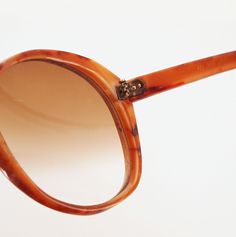 Dating from the late 70s by my estimate, these sunglasses have large gradient brown plastic lenses The frames are marbled opaque plastic in shades of reddish brown. '399 Japan' is barely visible stamped inside one arm. Condition: Just good. I would call the lenses pretty scratched (zoom in to see) and the frames also have some nicks and scratches. Although they do not appear bent at all, when you fold in the arms, they cross rather crookedly (final photo). Still, so cool. Size: The lenses themse Vintage Tortoiseshell Sunglasses With Gradient Lenses, Vintage Sunglasses With Gradient Lenses, Vintage Plastic Sunglasses With Uva Protection, Vintage Tortoiseshell Wayfarer Sunglasses, Vintage Brown Sunglasses For Summer, Vintage Plastic Sunglasses With Tinted Lenses, Vintage Sunglasses With Tinted Plastic Lenses, Vintage Brown Sunglasses With Mirrored Lenses, Vintage Tortoiseshell Sunglasses For Summer